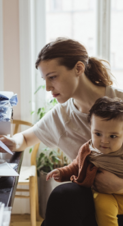 Businesswoman reading document while sitting with baby boy in living room.