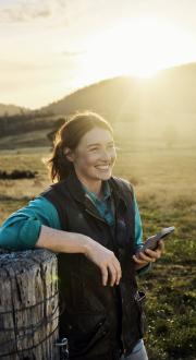 A woman holding a mobile phone on a farm.