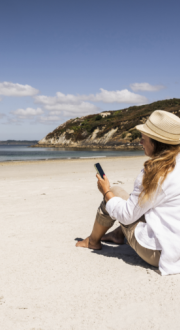 Woman using mobile phone on a beach on a sunny day.