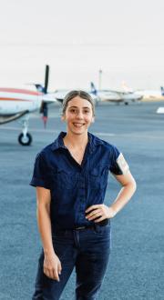 Woman standing in front of planes on a tarmac.