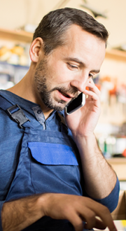 Male shopkeeper using a laptop and mobile device.