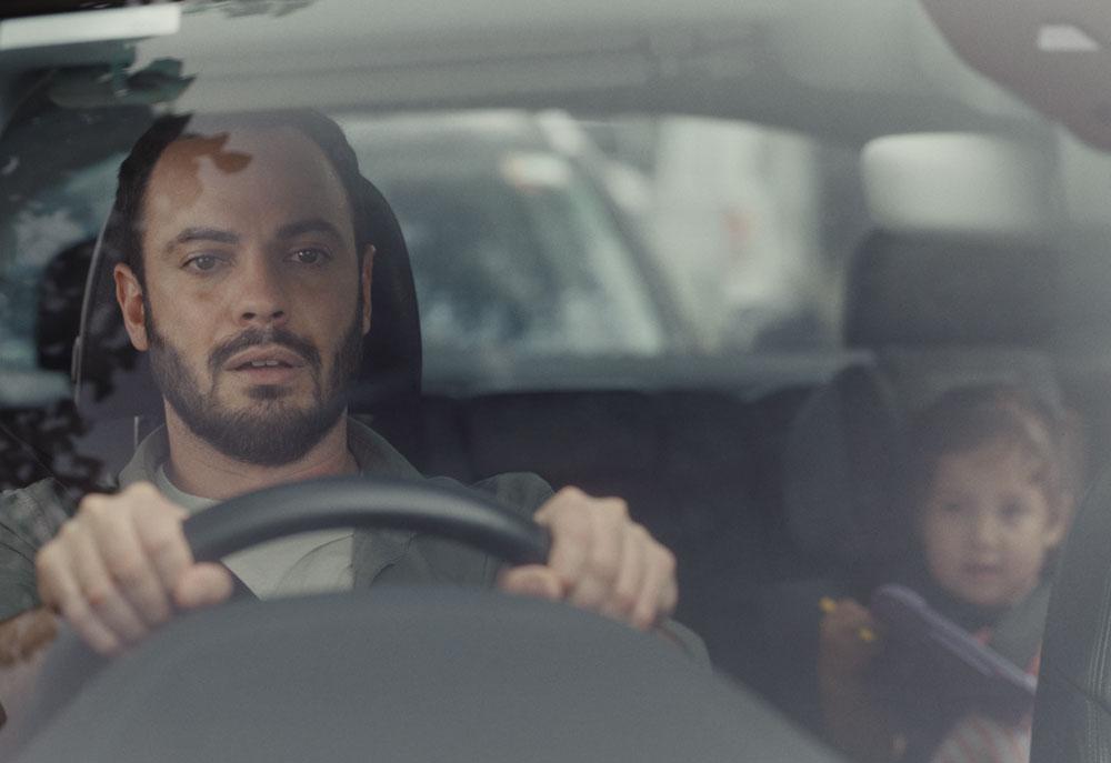 man driving a car with a child in the back seat